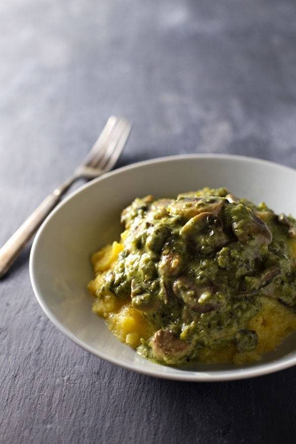 Creamy Poblano Mushrooms with Polenta in a white bowl with a fork.