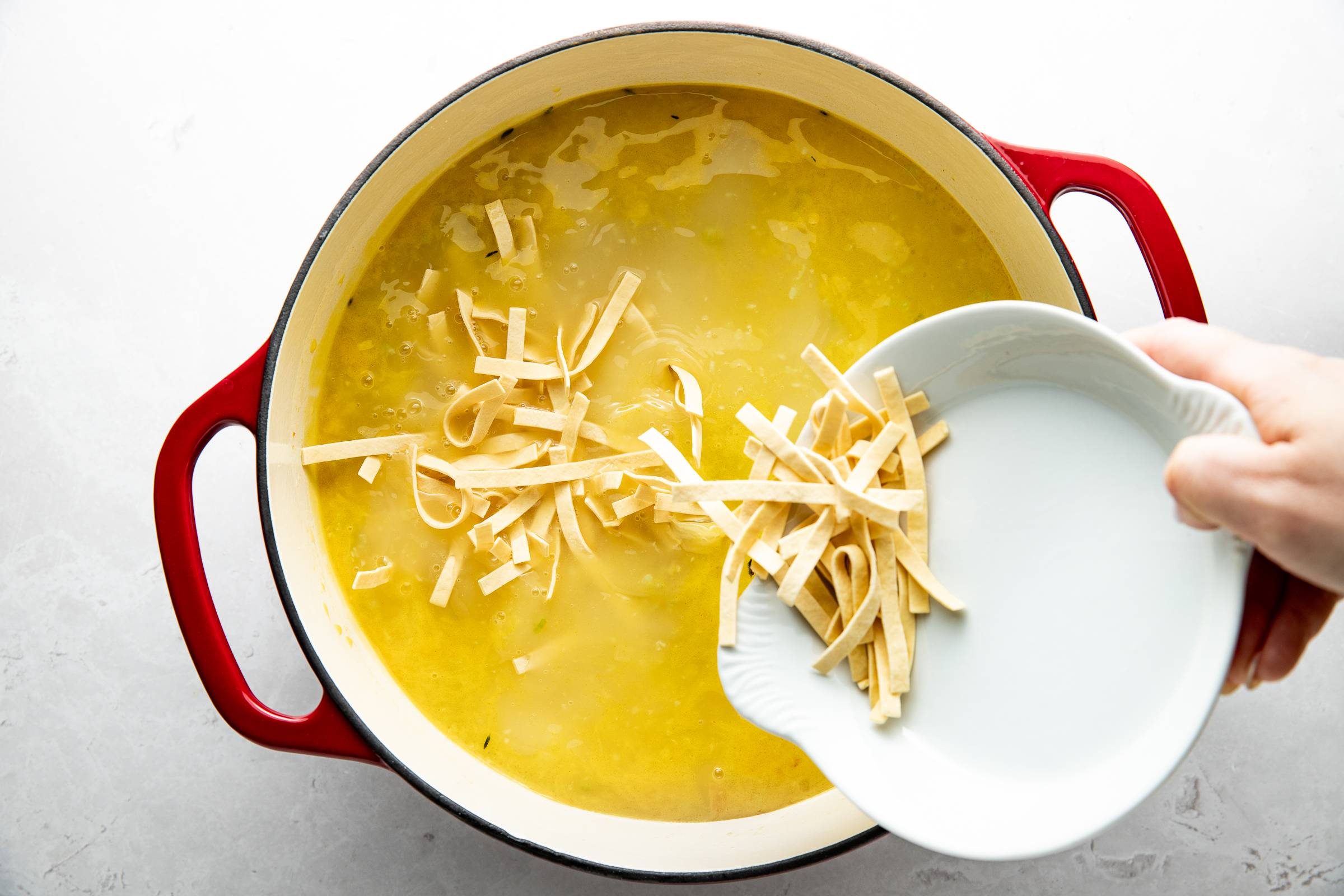 Adding noodles to chicken soup.