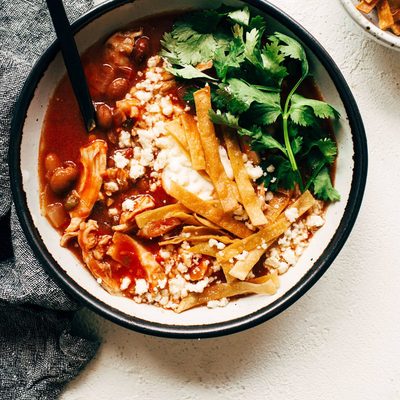 Chicken Tortilla Soup in a bowl with toppings and a spoon.