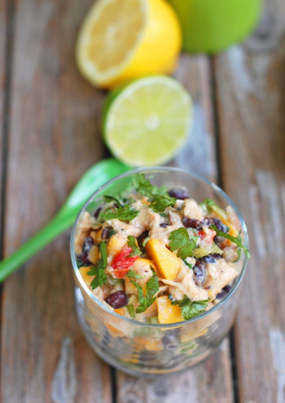 Mango chicken salad in a glass dish with lemons and limes.