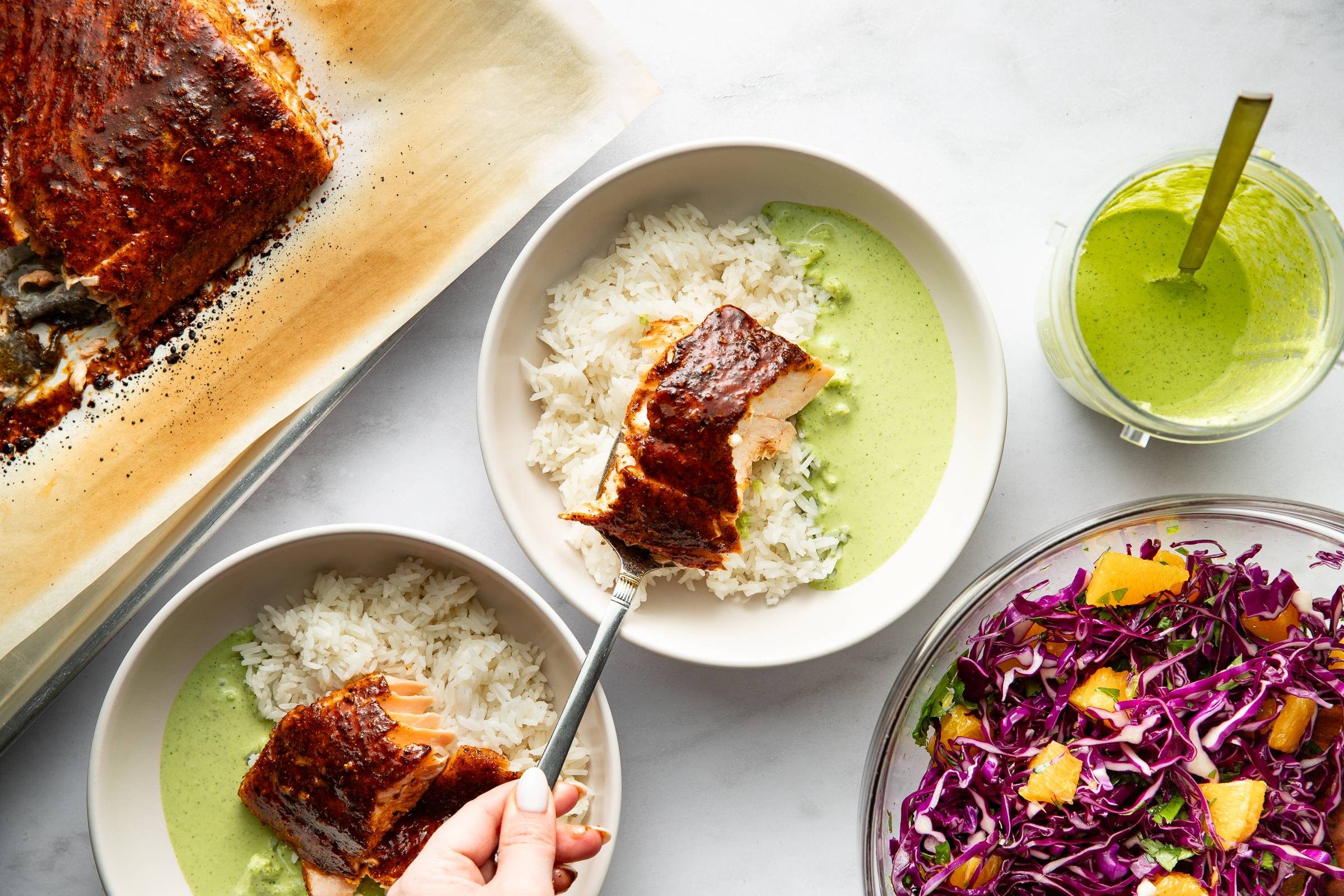 Plating chipotle salmon in bowls with rice and aji verde.